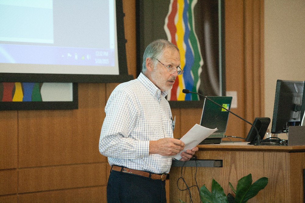A man reads from a paper into a podium microphone